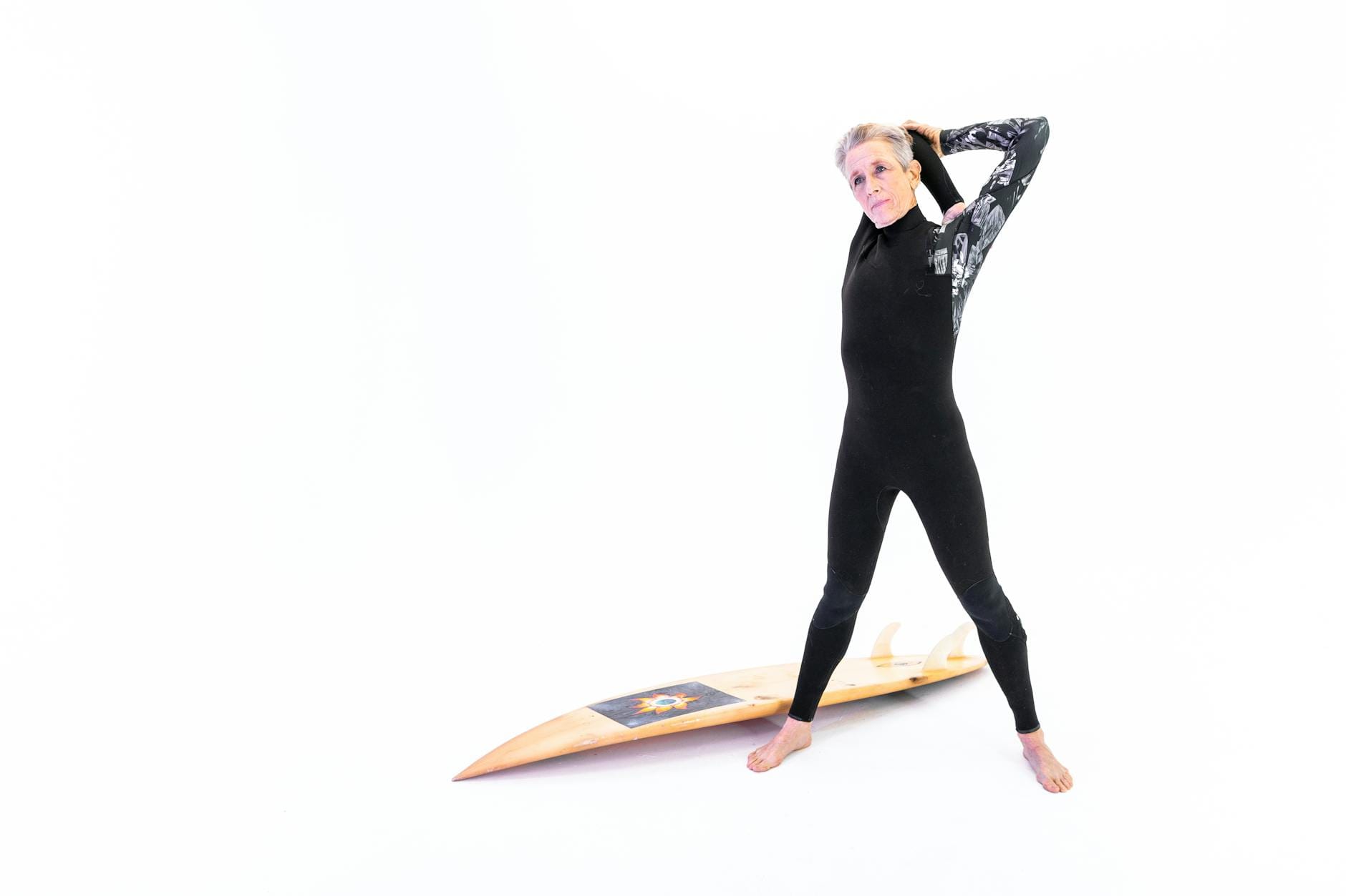 Starsza kobieta w piance surfingowej trzymająca deskę w domu