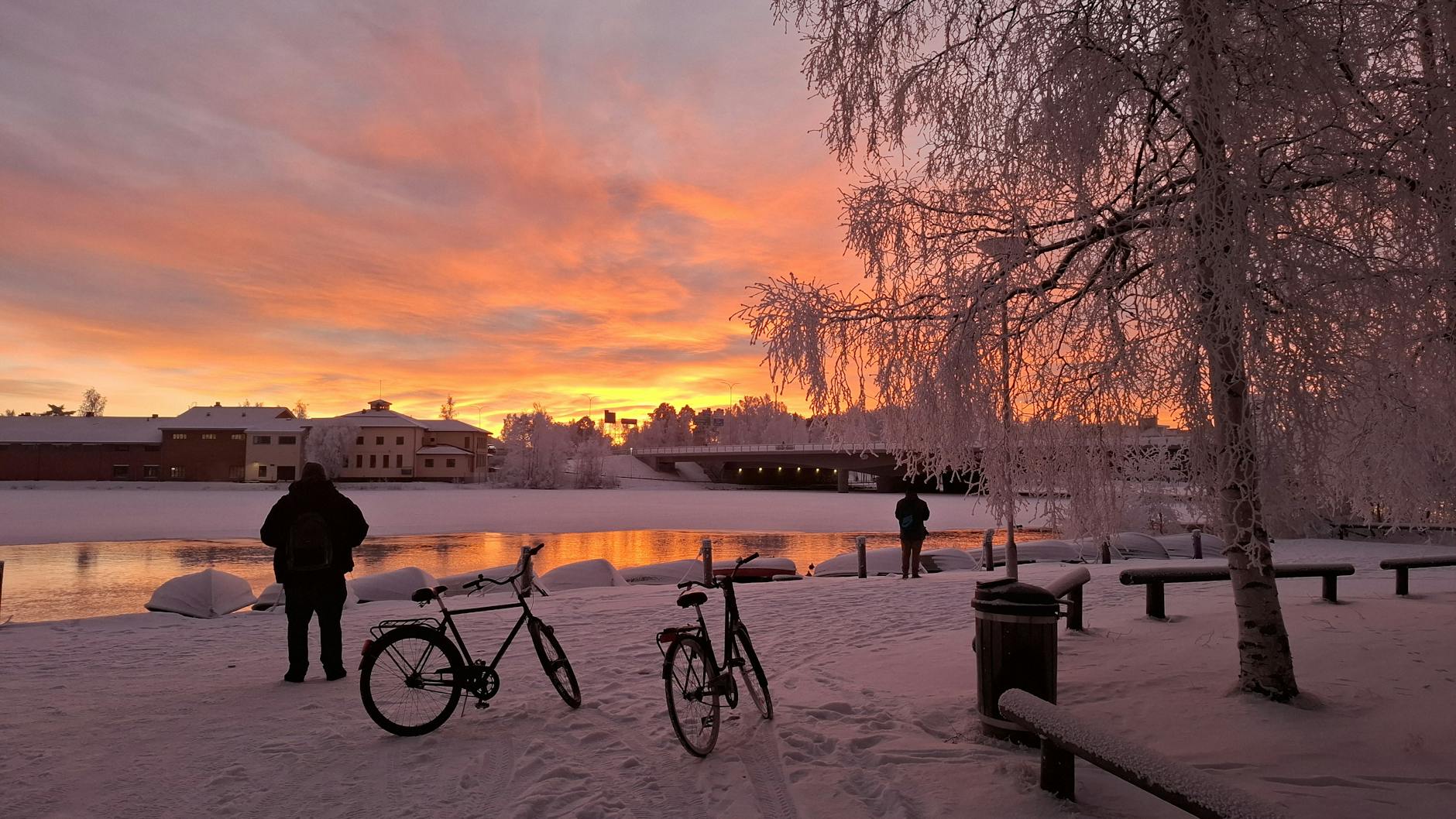Zimowy zachód słońca nad ośnieżonym krajobrazem i zamarzniętą rzeką